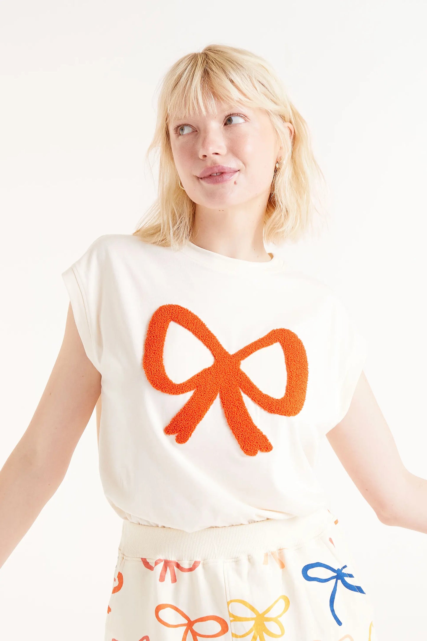 Camiseta Print Lazo. Camiseta blanca con bordado de lazo rojo en relieve, cuello redondo y mangas cortas.