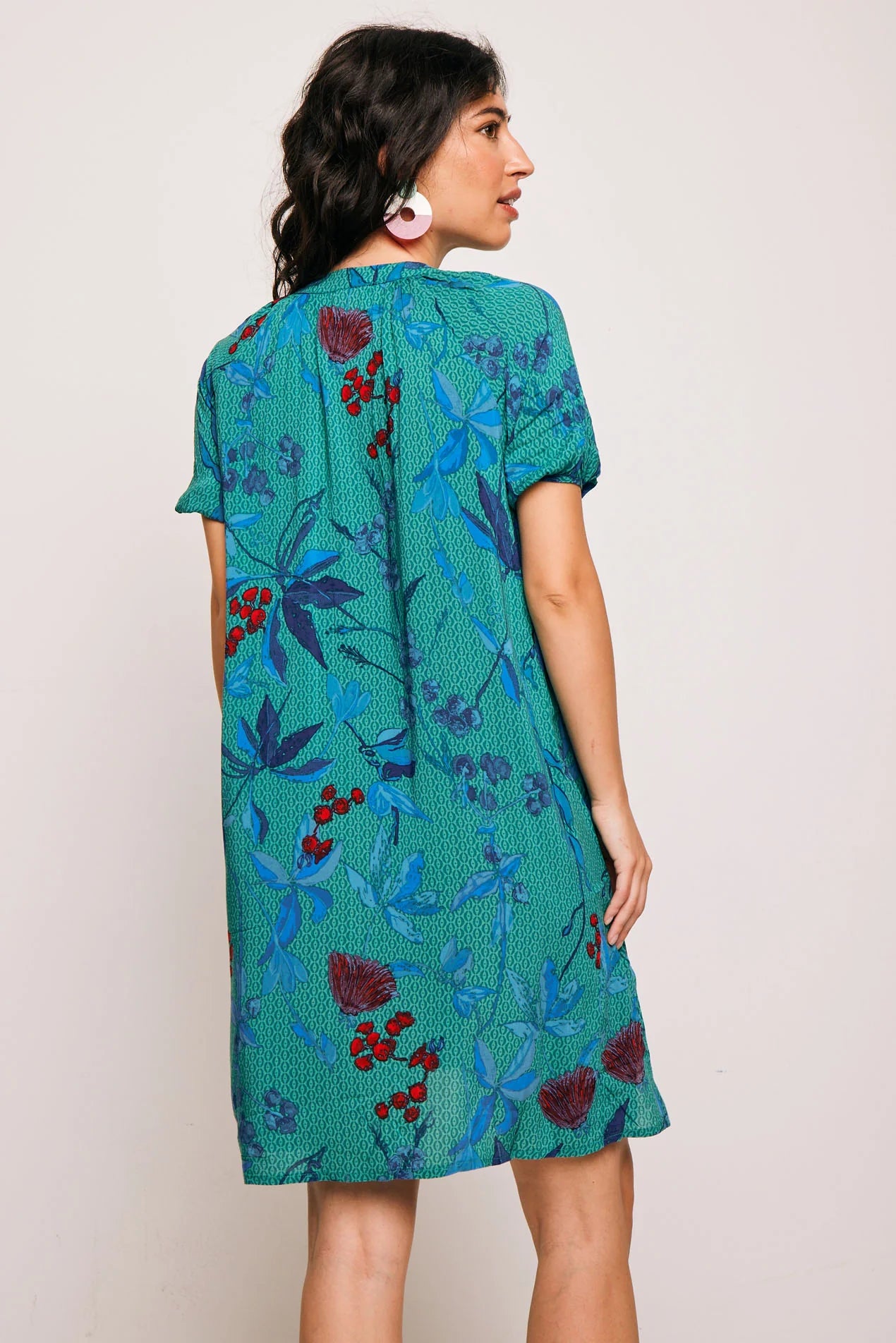 Vestido Famara Smile corto de algodón con estampado tropical en tonos verdes y rojos. Diseño amplio con escote en V y manga corta, ideal para verano.