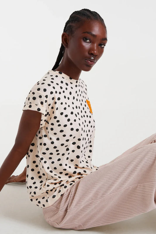 Camiseta Tano Dots de Compañía Fantástica Crudo y Negro con estampado de topos irregulares, combinada con pantalón beige de canalé. Estilo casual moderno.