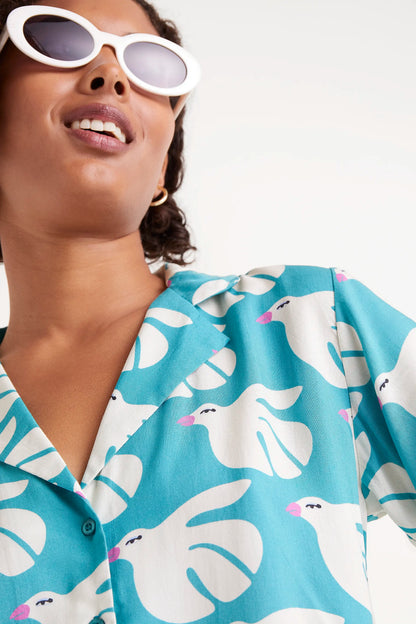 Camisa Rayon Estampado Dove. Camisa de manga corta con estampado de palomas blancas sobre fondo azul turquesa.
