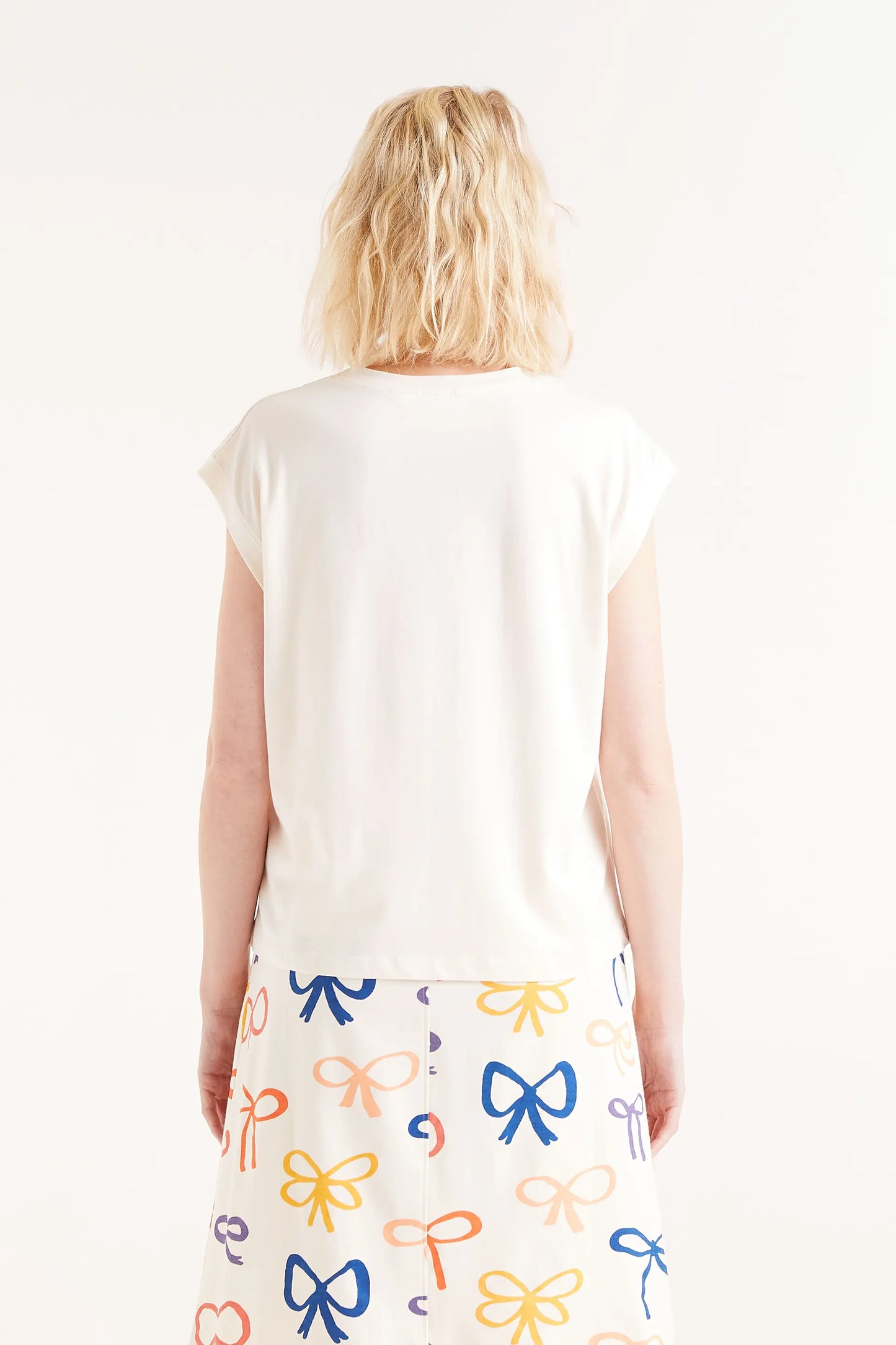 Camiseta Print Lazo. Camiseta blanca con bordado de lazo rojo en relieve, cuello redondo y mangas cortas.