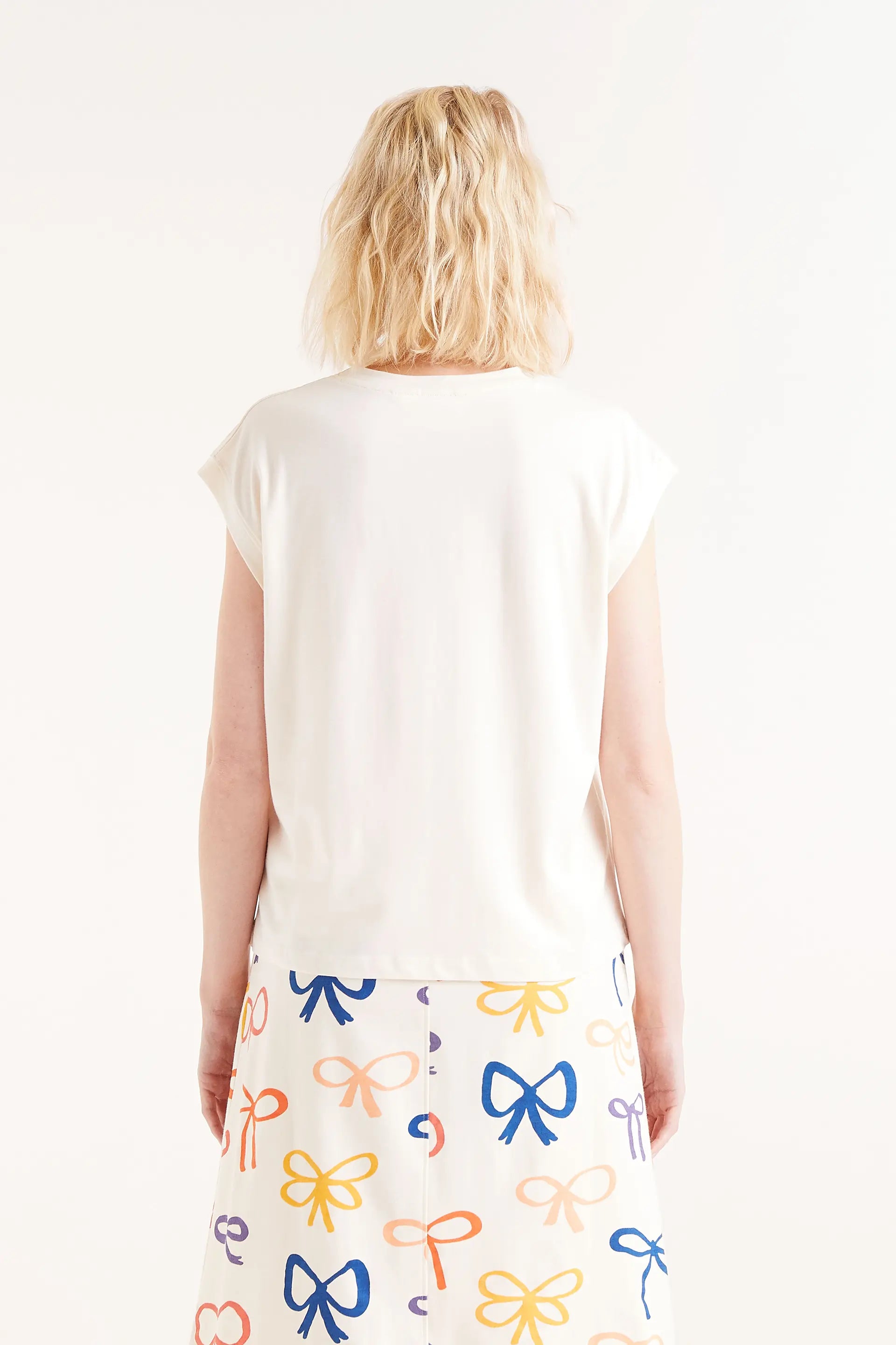 Camiseta Print Lazo. Camiseta blanca con bordado de lazo rojo en relieve, cuello redondo y mangas cortas.