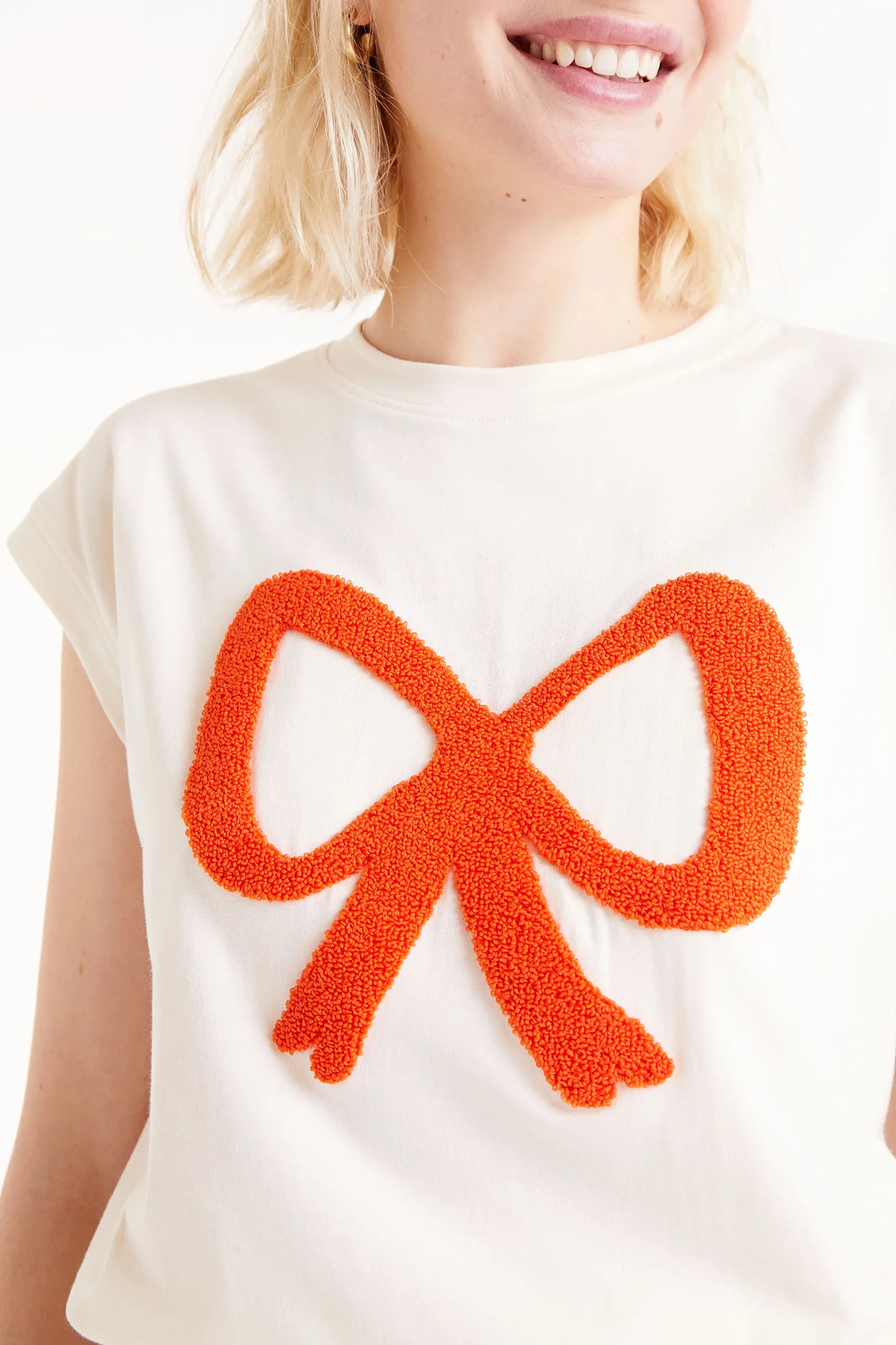 Camiseta Print Lazo. Camiseta blanca con bordado de lazo rojo en relieve, cuello redondo y mangas cortas.