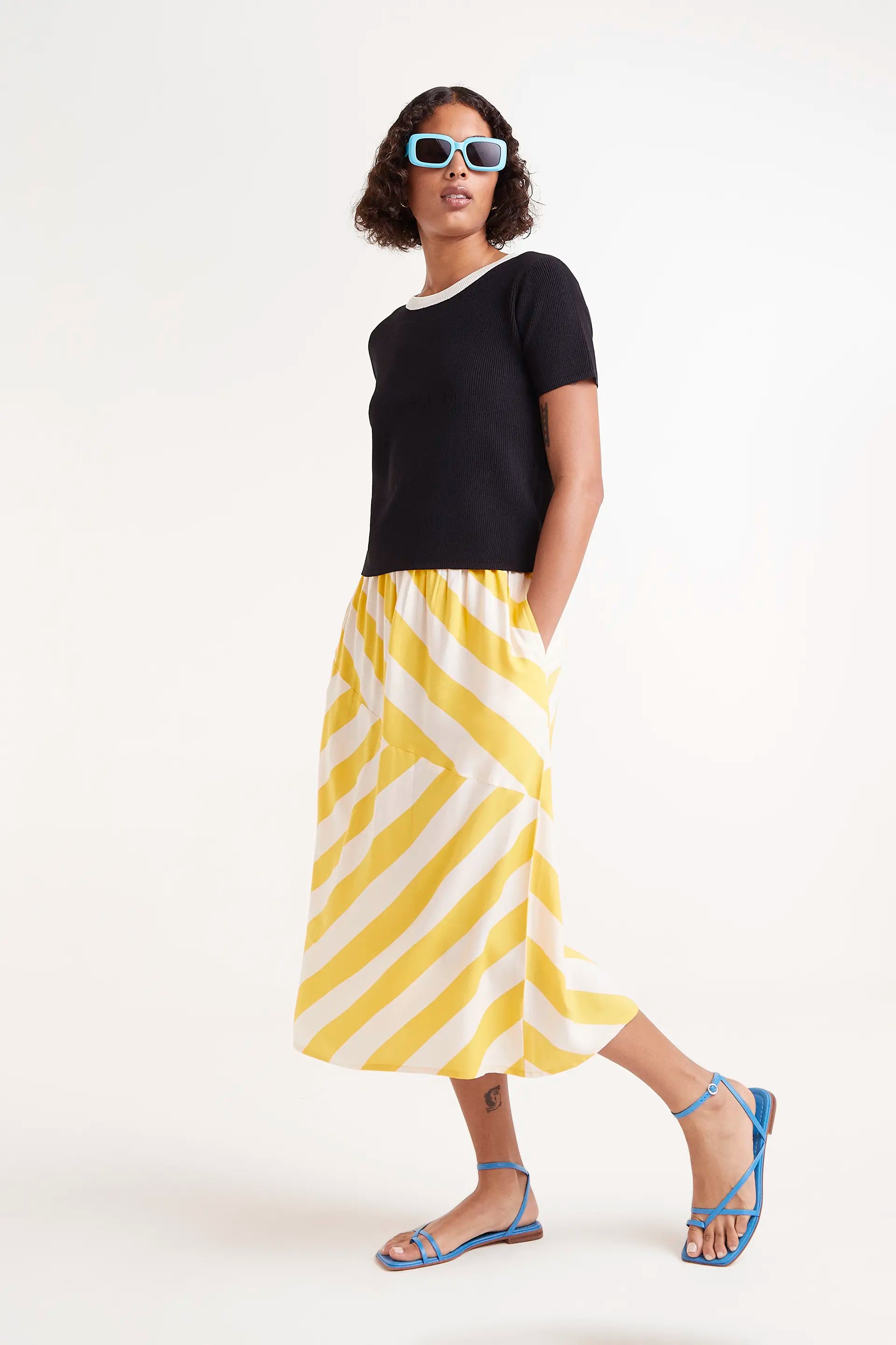 Falda Midi Rayas Amarillas. Falda midi con rayas amarillas y blancas, cintura elÃ¡stica y corte fluido.