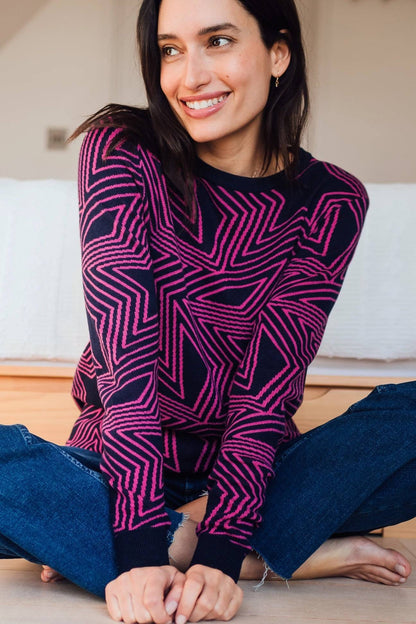 Jersey Rosie Sugar Hill Brighton multicolor con estampado de estrellas en tonos rosa y azul, modelo sentada con jeans casuales.