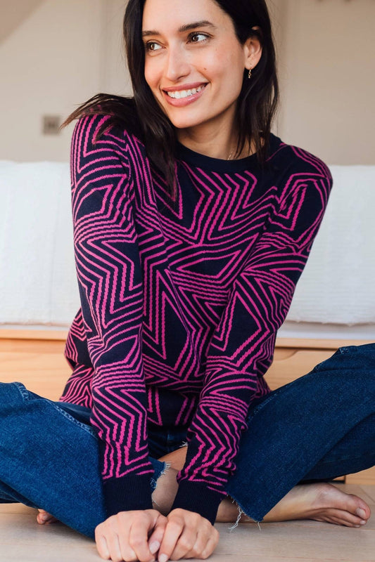 Jersey Rosie Sugar Hill Brighton multicolor con estampado de estrellas en tonos rosa y azul, modelo sentada con jeans casuales.