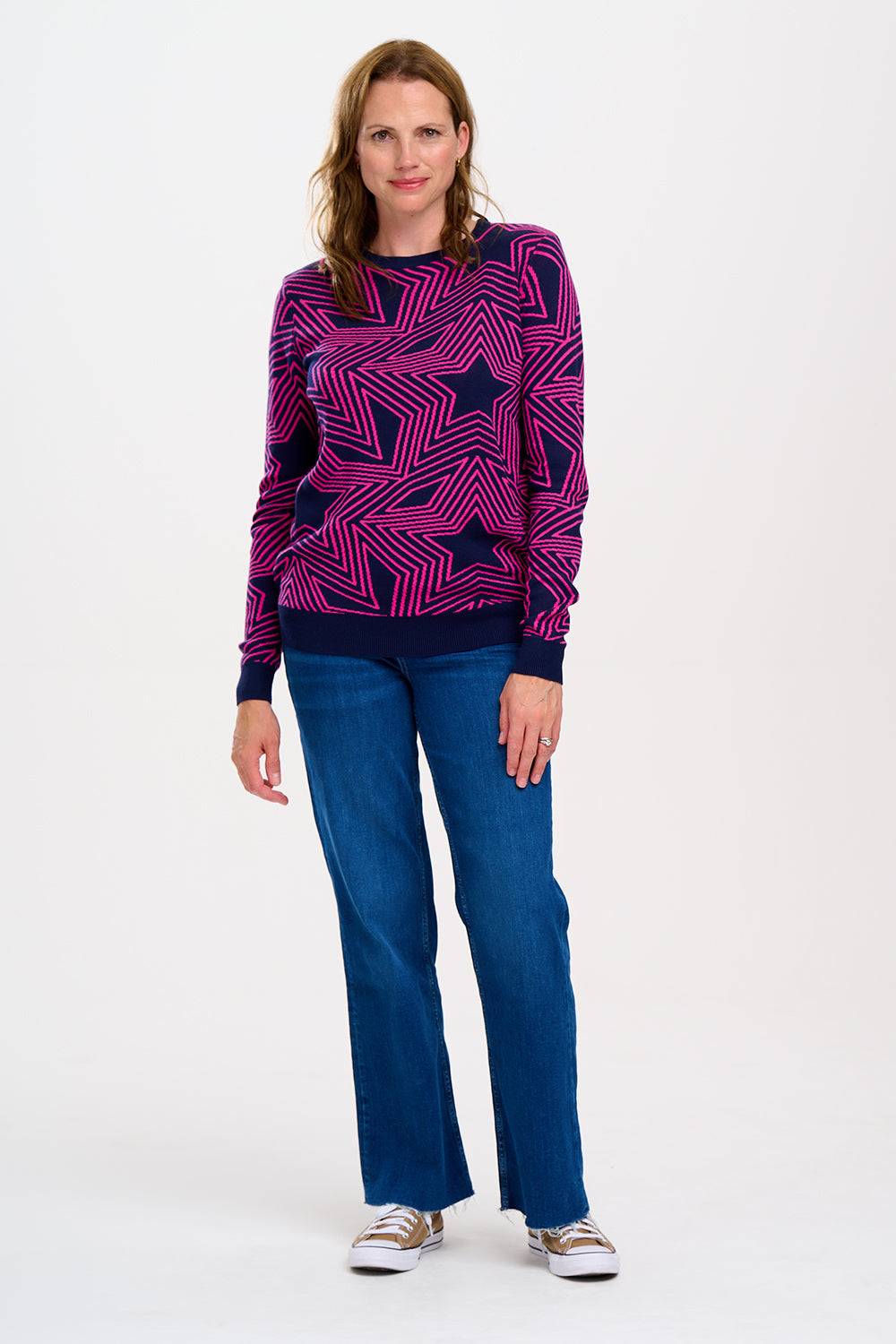 Jersey Rosie Sugar Hill Brighton multicolor con diseño de estrellas geométricas, combinado con jeans rectos y zapatillas.