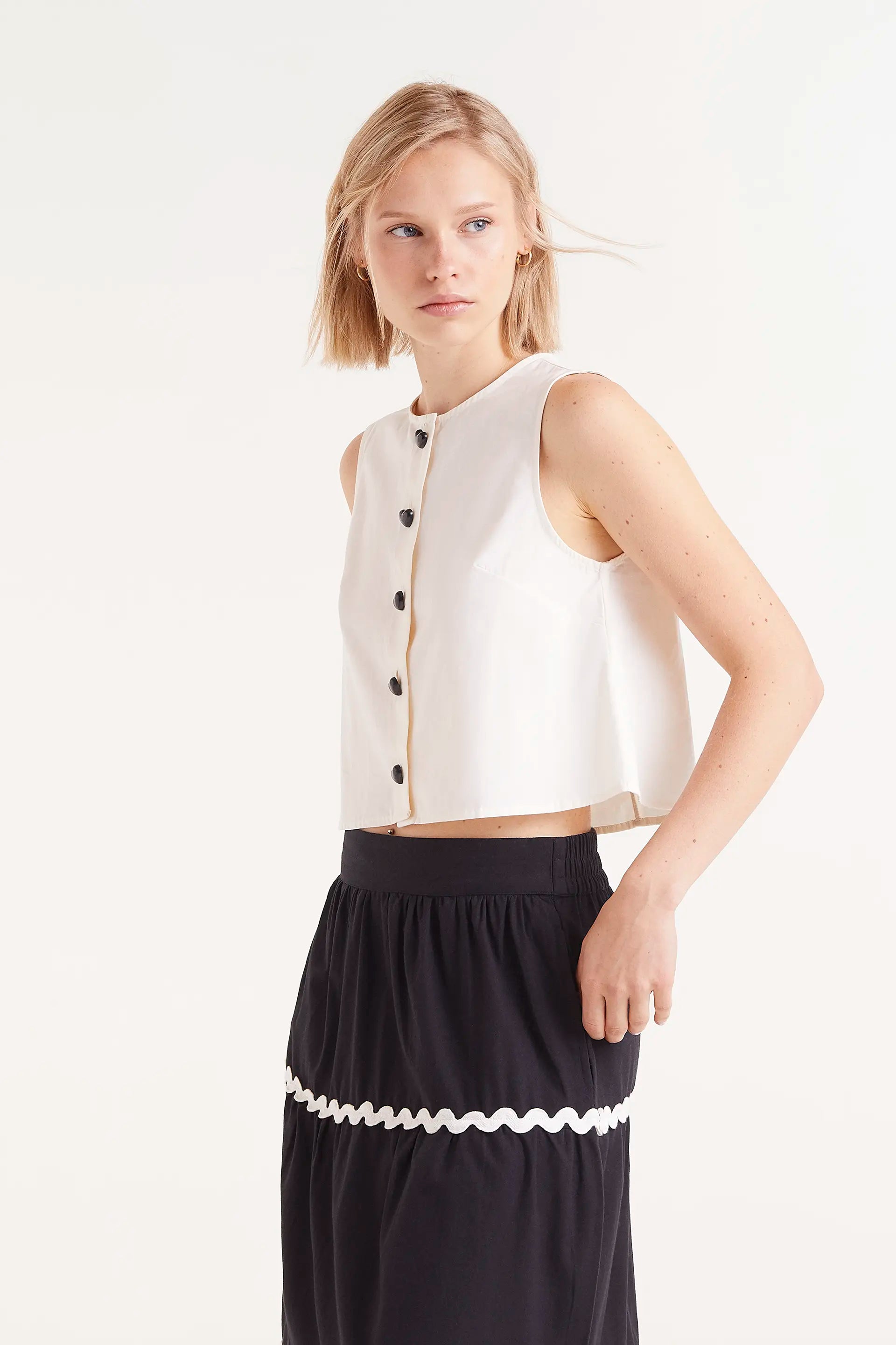Top Sin Mangas Con Botones Blanco. Top blanco sin mangas con botones negros en la parte frontal.