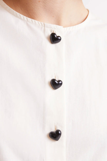 Top Sin Mangas Con Botones Blanco. Top blanco sin mangas con botones negros en la parte frontal.