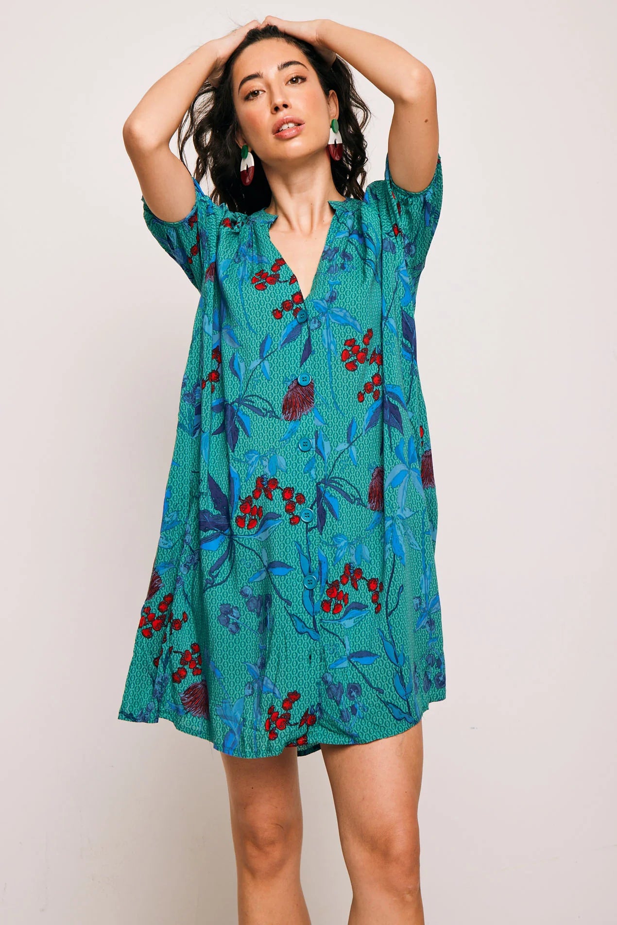 Vestido Famara Smile corto de algodón con estampado tropical en tonos verdes y rojos. Diseño amplio con escote en V y manga corta, ideal para verano.