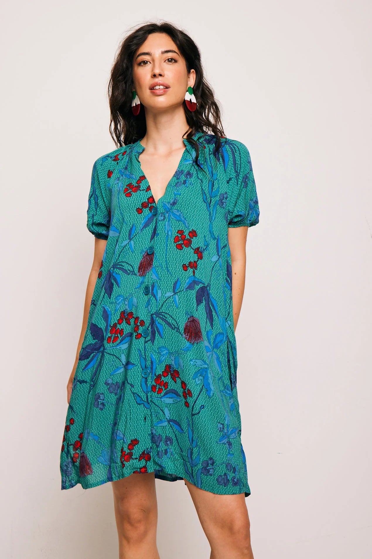 Vestido Famara Smile corto de algodón con estampado tropical en tonos verdes y rojos. Diseño amplio con escote en V y manga corta, ideal para verano.