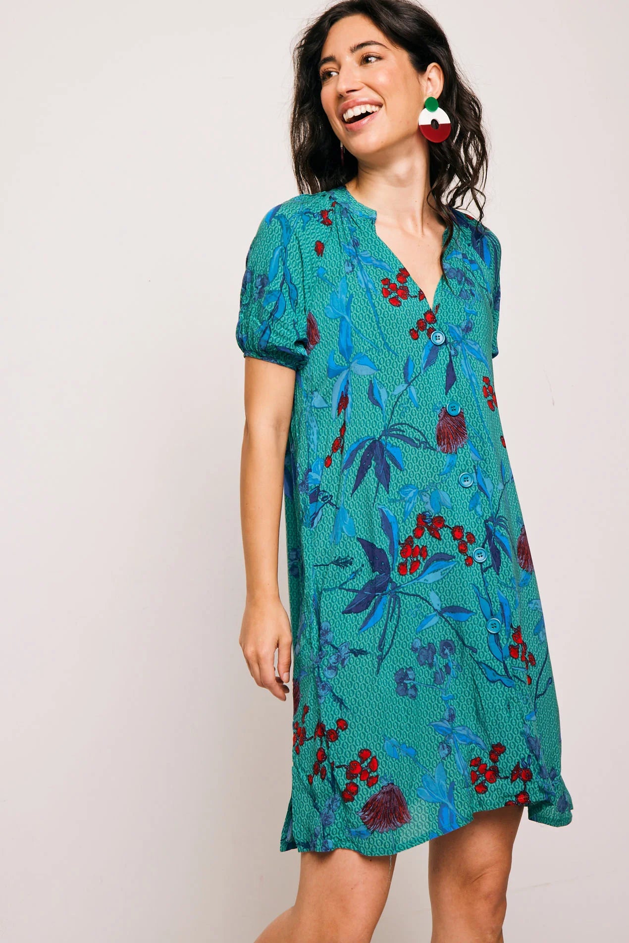 Vestido Famara Smile corto de algodón con estampado tropical en tonos verdes y rojos. Diseño amplio con escote en V y manga corta, ideal para verano.