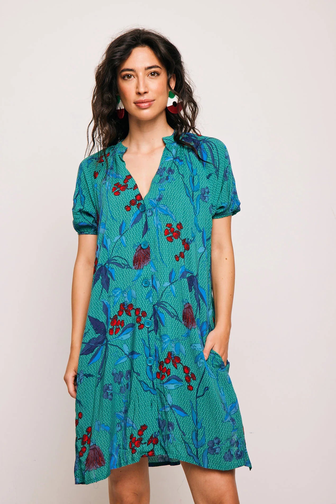 Vestido Famara Smile corto de algodón con estampado tropical en tonos verdes y rojos. Diseño amplio con escote en V y manga corta, ideal para verano.